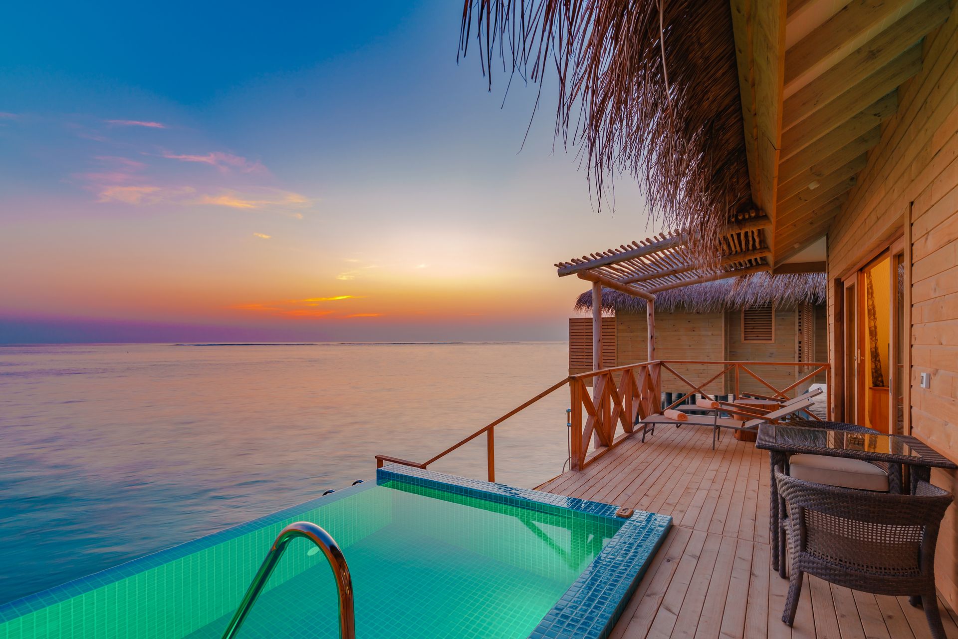 Overwater bungalows at sunset over a turquoise lagoon