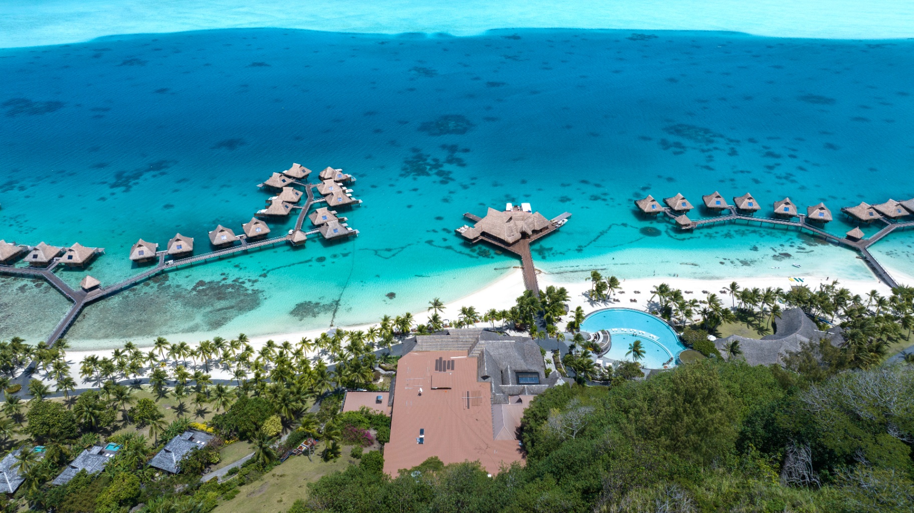 Aerial view of a Bora Bora resort with overwater bungalows over a turquoise lagoon